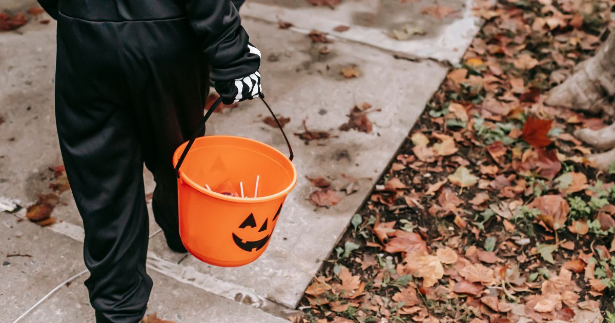 A child holding an orange trick or treat bucket